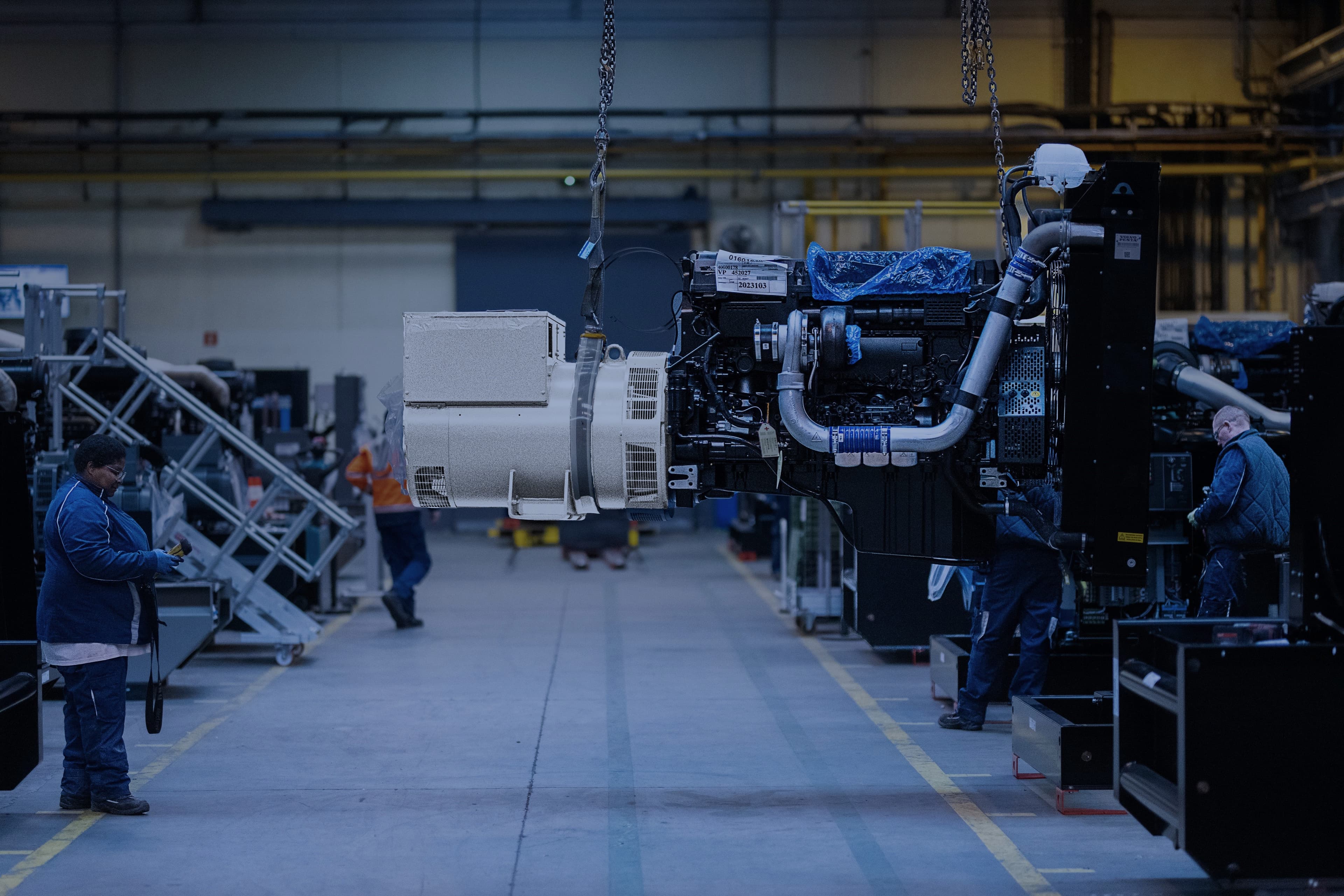 A production operator is handling a generator sets using an overhead crane